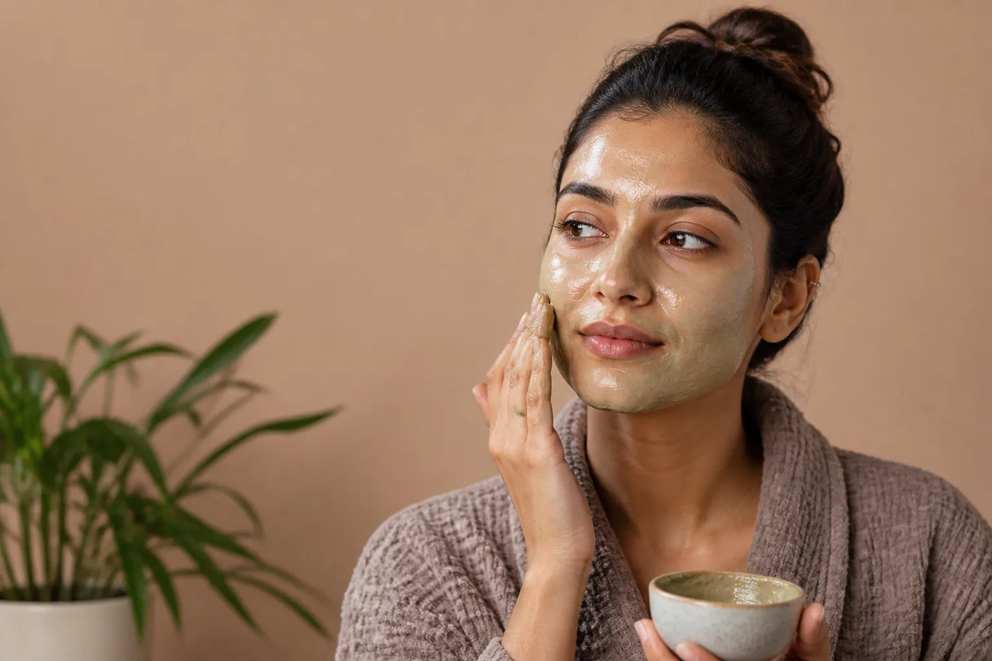 Woman with medium olive skin applying a face mask