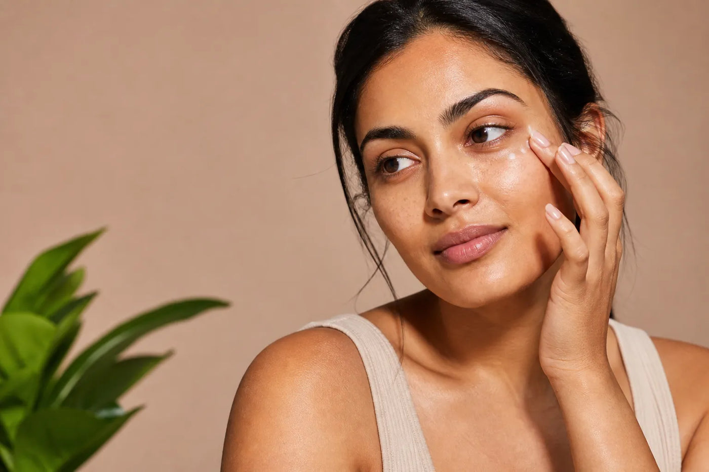 Woman with medium olive skin applying eye cream