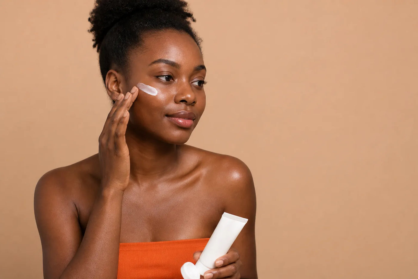 Woman with deep brown skin applying sunscreen
