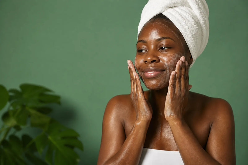 Woman with deep brown skin washing her face